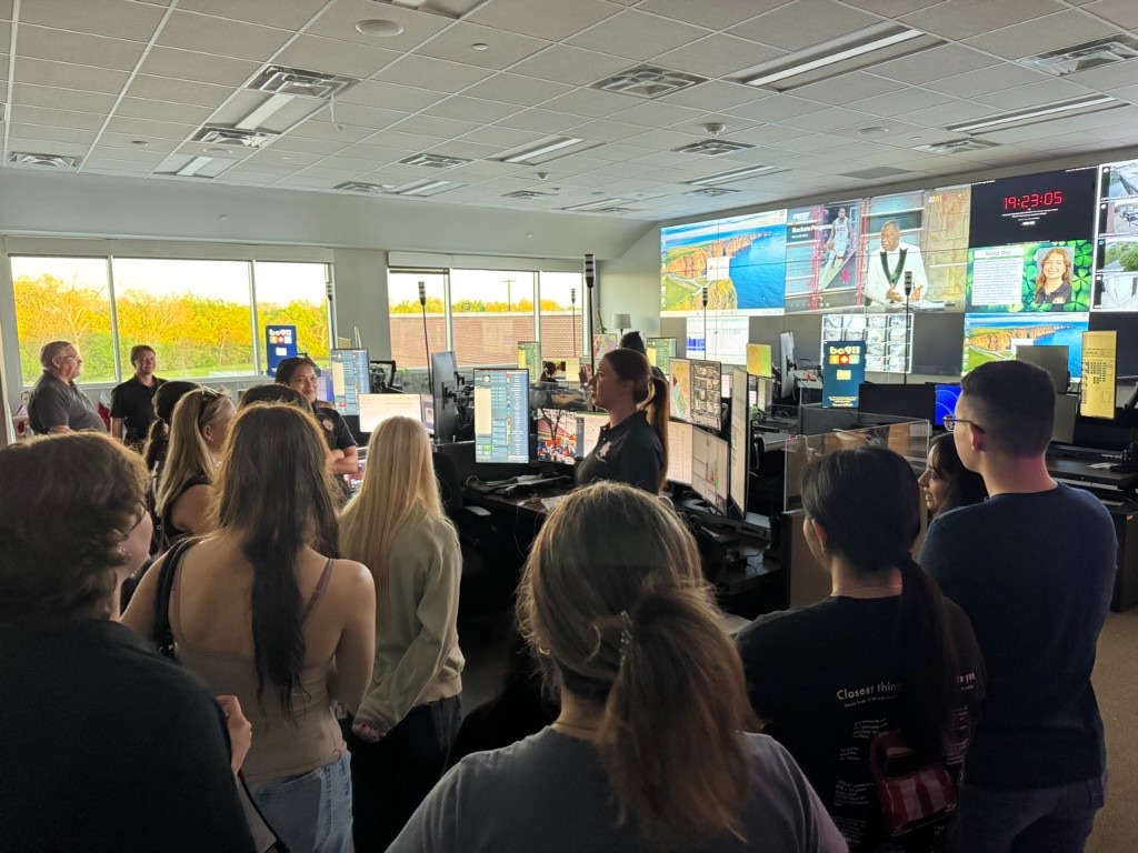 AGILE students on a tour of College Station Police Department dispatch, gathered around workstations and a video wall.